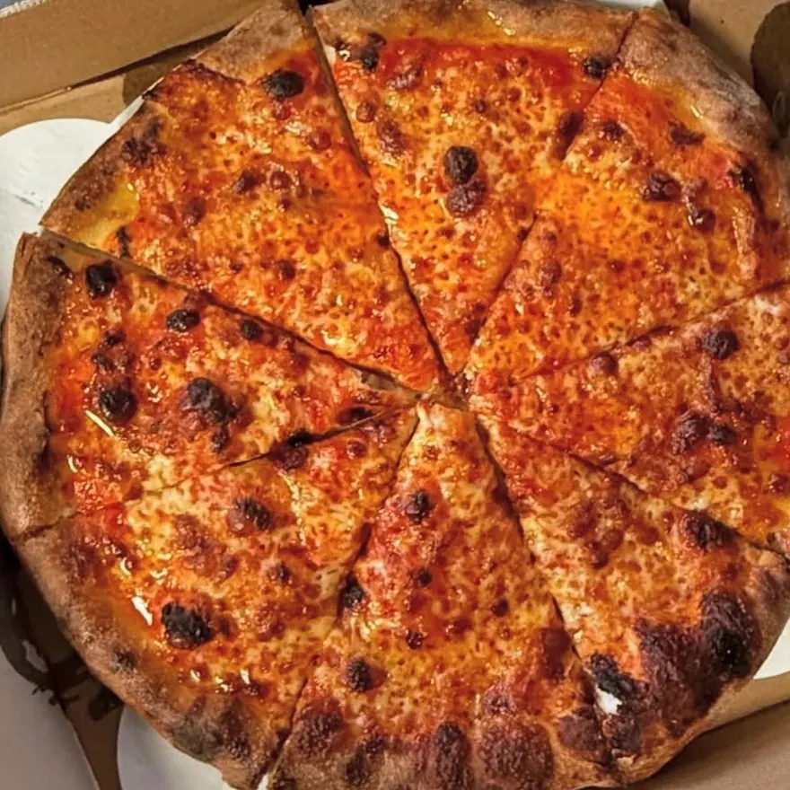 Charred-crust cheese pizza cut in a pizza box